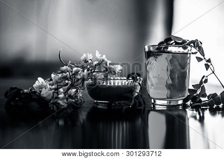 Bunch Of Flowers Of Drumstick On Wooden Surface Along With Its Extracted Water Or Tincture In A Glas