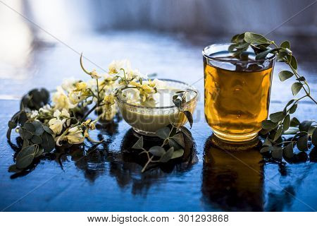 Bunch Of Flowers Of Drumstick On Wooden Surface Along With Its Extracted Water Or Tincture In A Glas