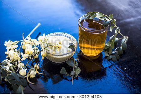 Bunch Of Flowers Of Drumstick On Wooden Surface Along With Its Extracted Water Or Tincture In A Glas