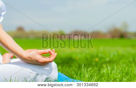 Meditation. Woman Is Meditating Sitting In Lotus Pose On Grass At The Park. Girl Doing Ardha Padmasa