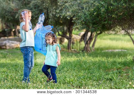 Two Kids Volunteer Cleaning Plastic Pollution In Summer Park. Children With Garbage Bags Cleaning Up