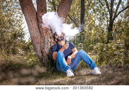 Handsome Vaper Enjoying An Electronic Smoke Device. Modern Ways Of Quitting Tobacco.