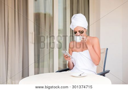 Happy Smiling Woman In Under-eye Patches Readind Sms Message And Drinking Coffee At Hotel Terrace Re