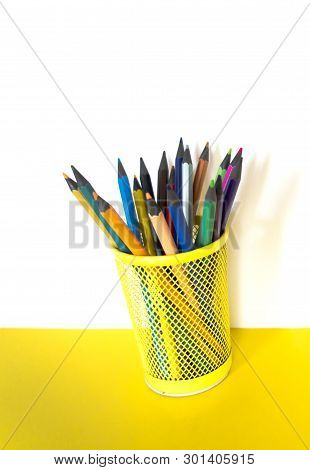 Color Pencils In A Yellow Glass On A Yellow Table On A White Background