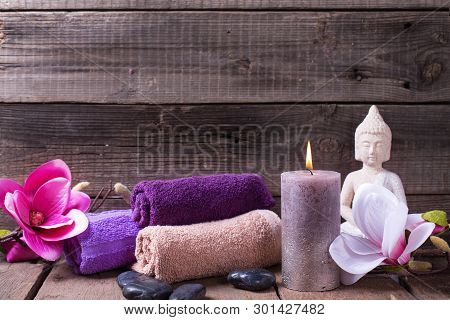 Set Of Towels For Spa, Burning Candle, Black Stones, Buddha And Pink  Flowers On  Rustic Textured Wo