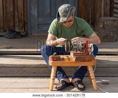 The Caucasian Man Is Working With The Portable Grinder And Polishing The Fishing Spoons On The Porch