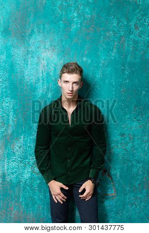 The Guy Stands Near The Wall And Looks Intently. Looking Interested