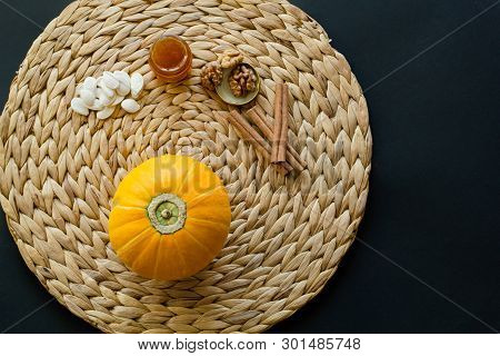 Small Pumpkin With Seeds, Little Glass Can Of Honey, Walnuts And Cinnamon Sticks On A Circle Mat/nap