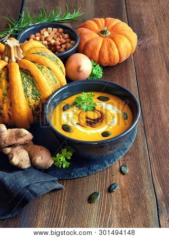 Spicy Pumpkin Soup With Ginger And Onion, Served In Black Bowl With Pumpkin Oil, Cream, Pumpkin Seed