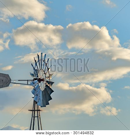 Clear Square Windpump With A Snow Covered Mountain And Cloudy Blue Sky In The Background