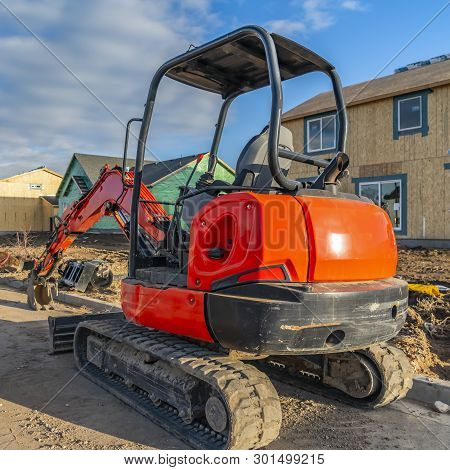 Square Red Excavator On A Construction Site For New Homes Against Cloudy Blue Sky