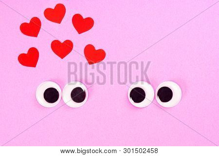 Googly Eyes Of Strange Pair Of Lovers On Rose Background With Some Small Hearts. Close Up Toy Eyes.