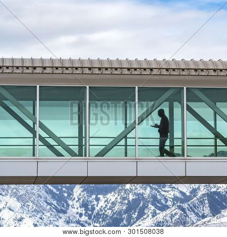 Clear Square Skybridge With A Silhouette Of A Man Seen Through The Clear Glass Wall