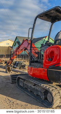 Clear Vertical Red Excavator On A Construction Site For New Homes Against Cloudy Blue Sky