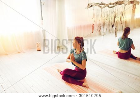 mindfulness, spirituality and healthy lifestyle concept - woman meditating at yoga studio with soft sunlight