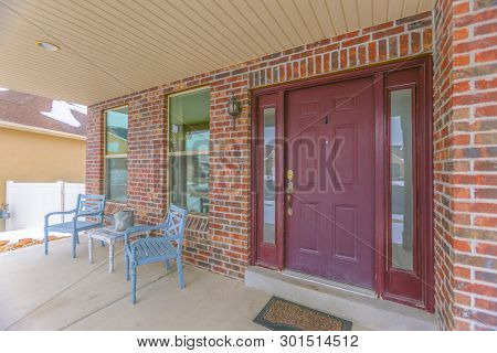 Facade Of A Home With A Red Front Door And Reflective Sidelights And Windows