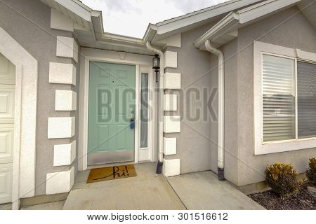 Green Front Door With Sidelight On The Facade Of Home Viewed Against Cloudy Sky