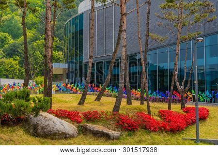 Muju,south Korea; May 1, 2019: Trees, Flowers And Pinwheels In Front Of Exterior Glass Of National T