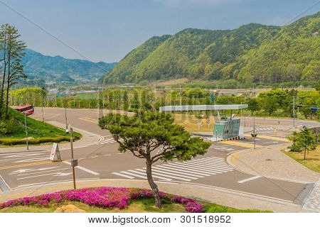 Muju,south Korea; May 1, 2019: Trimmed Evergreen Tree And Purple Azaleas On Corner Of Entrance Gate 
