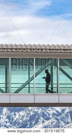 Clear Vertical Skybridge With A Silhouette Of A Man Seen Through The Clear Glass Wall