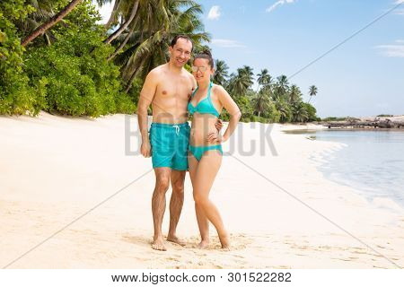 Portrait Of A Smiling Young Couple Looking To Camera At Beach