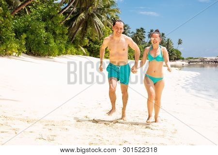 Happy Young Couple Running On Beach Enjoying The Vacations