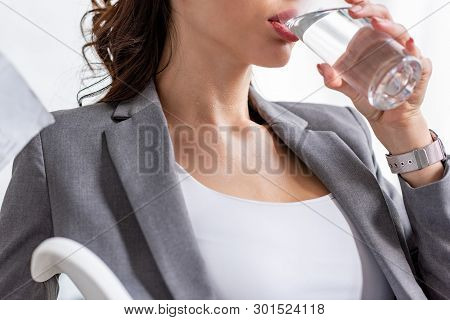 Partial View Of Young Businesswoman Drinking Water From Glass While Suffering From Heat In Office