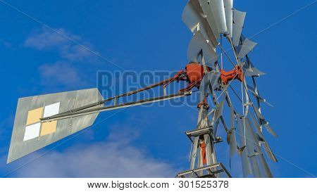 Panorama Close Up Of A Windpump With Vibrant Blue Sky And Puffy Clouds In The Background
