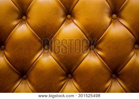 The Brown Soft Leatherette Background With Asymmetrical Buttons. Soft And Expensive Furniture Elemen