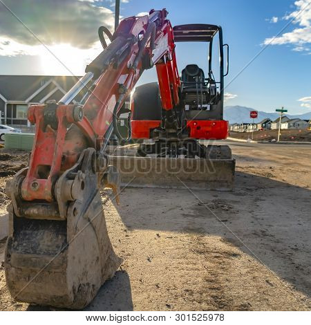 Square Close Up Of A Red Excavator With An Attched Grader Blade Viewed On A Sunny Day