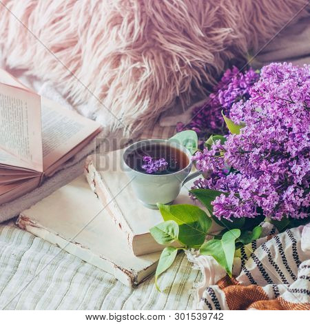 Still Life Details In Home Interior Of Living Room. Sweaters And Cup Of Tea With Lilac Flowers And S