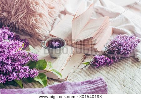 Still Life Details In Home Interior Of Living Room. Sweaters And Cup Of Tea With Lilac Flowers And S