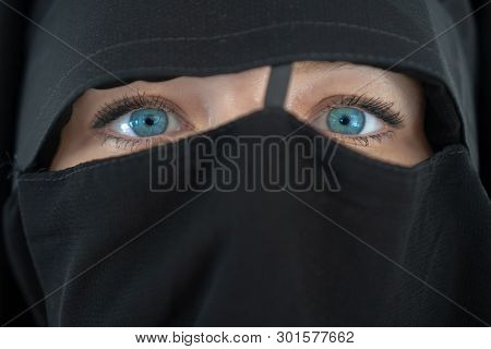 Young Woman With Blue Eyes In Black Nibe Close Up. The Girl In The Burqa. People Religious Lifestyle