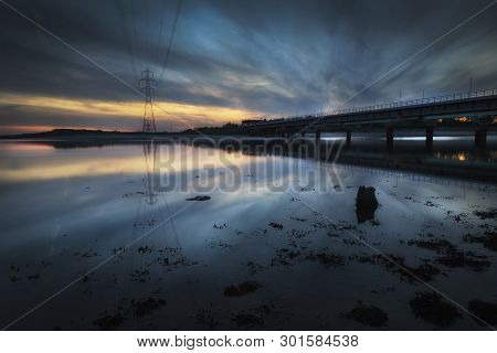 Sunset At The Railway Line Crossing Over The Loughor Estuary From Swansea To Llanelli In South Wales