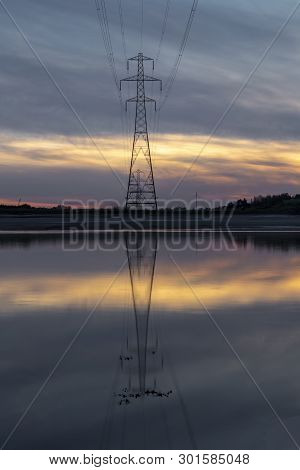 Pylon Reflection In After Sunset On The Loughor Estuary, Llanelli, South Wales, Uk