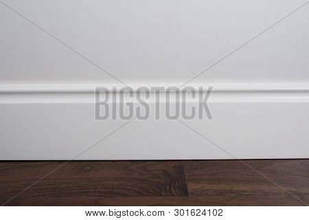 Light Matte Wall, White Baseboard And Tiles Immitating Hardwood Flooring
