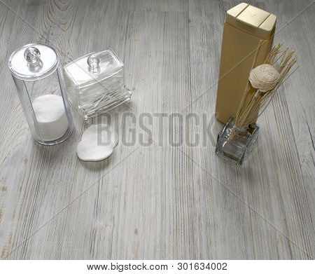 Cosmetic Flatlay On Grey Wooden Table. Beauty Set Of Plastic Containers With Q-tips, Disks And Flowe