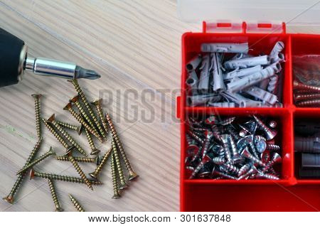 Electric Screwdriver And Screws On A Wooden Table.
