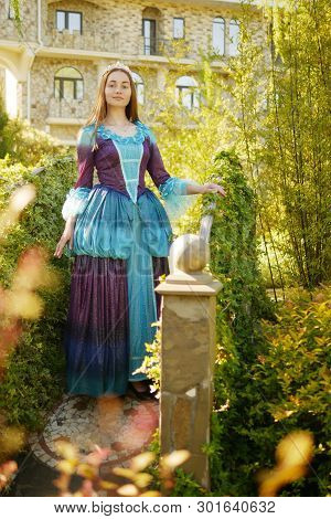 Girl Animator Dressed As A Medieval Princess On The Background Of The Castle In A Beautiful Park