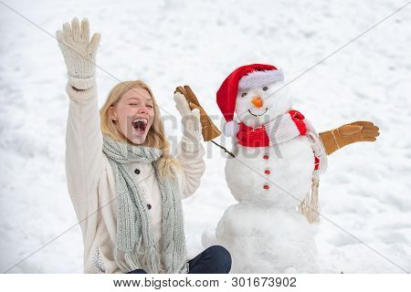 Excited Girl Plaing With A Snowman On A Snowy Winter Walk. Making Snowman And Winter Fun. Cute Snowm