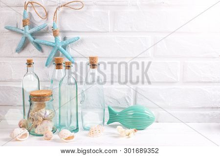 Nautical Or Marime Decorations Near By White Brick Wall. Decorative  Fish, Blue Bottles With Shells 