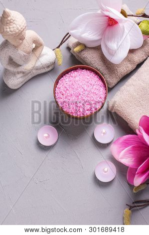 Sea Salt, Burning Candles, Buddha And Pink Magnolia Flowers On Grey Textured Background. Spa Concept