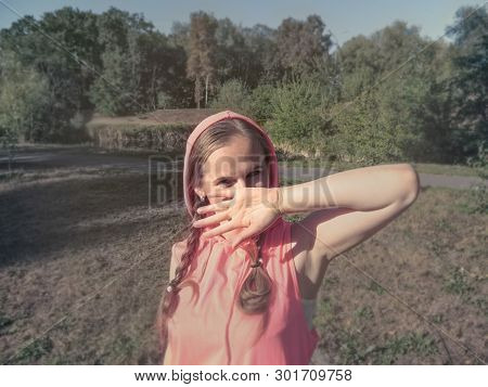 A Girl With Cheerful, Playful, Mischievous Eyes Covers Her Face With Her Hand. A Cute Young Woman In
