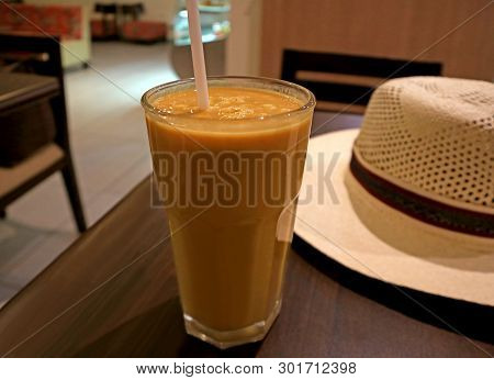 Glass Of Healthy Creamy Lucuma Fruit Juice Served On Wooden Table With A White Straw Hat, Ica Region