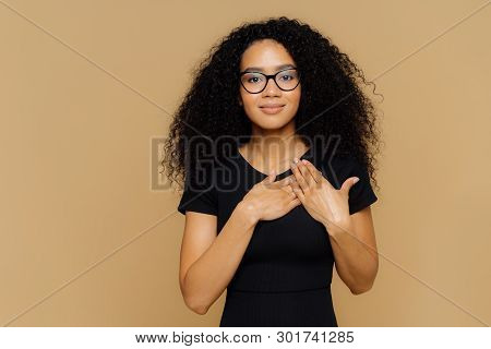 Beautiful Dark Skinned Woman Keeps Palms Near Hear, Expresses Gratitude, Thankfulness, Has Friendly 