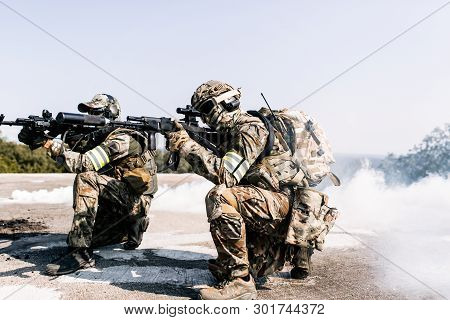 United States Army In Action, Camouflage And Army Helmet. Military Action In The Open Air, Smoke Gre