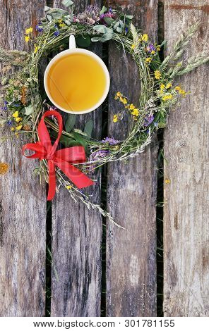 Herbal Tea Of Medical Plants In A Cup On Weathered Wooden Boards Outdoors.