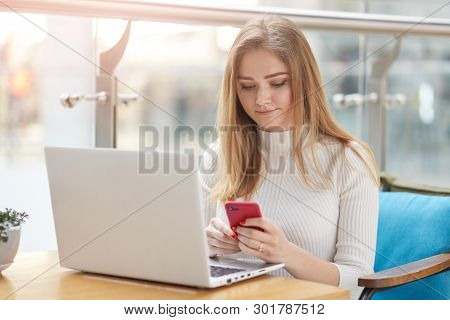 Photo Of Beautiful Young Blonde College Student Sitting On Blue Sofa In Front Of Lap Top In Cafe, Ch
