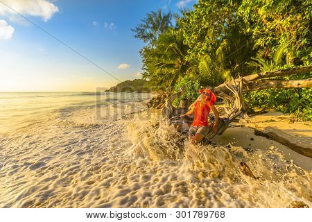 Funny Tourist Woman In Huge Splashing Wave At Anse Kerlan, Praslin Island, Seychelles. Spectacular A