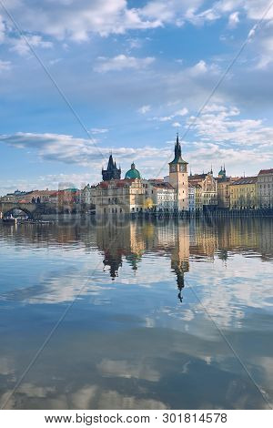 Charles Bridge And Historical Buildings In Prague Reflected In Calm Vltava River